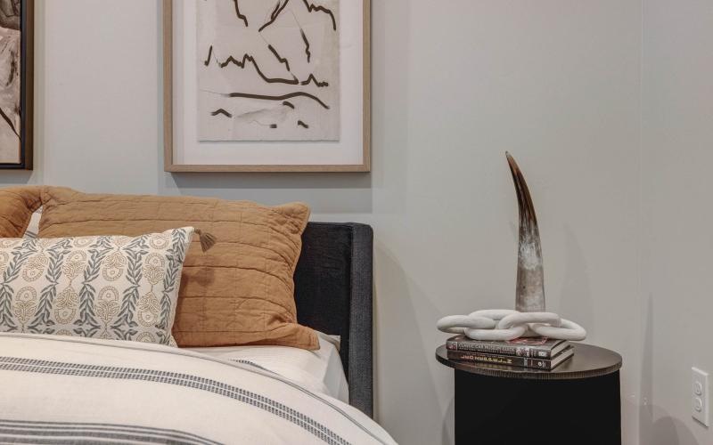 a bed with a pillow and a night stand with a vase on it