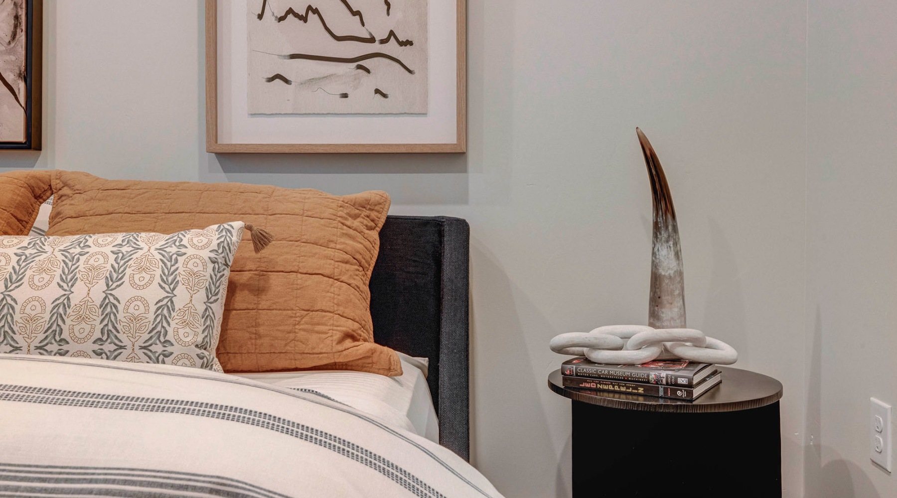 a bed with a pillow and a night stand with a vase on it